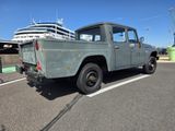 un camion vert garé sur un parking, avec un paquebot en arrière-plan