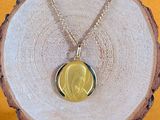 a close up of a gold necklace with a picture of a woman on it