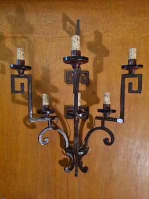 a metal candelier with candles on it on the wall