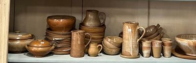 une étagère sur laquelle sont disposées de nombreuses pièces de poterie de styles variés