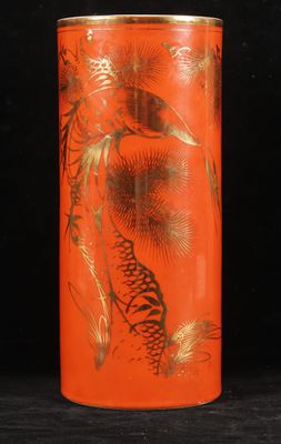 an orange vase with a gold design on it sitting on a black surface