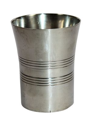 une tasse en argent posée sur une surface blanche