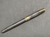 a close up of a pen on a table with a gray background