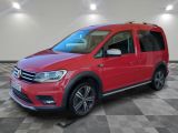 Une VW Tourer rouge est garée dans une pièce au sol à carreaux.