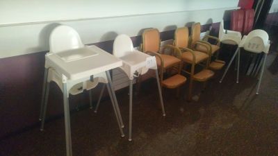 une rangée de chaises hautes pour bébés alignées contre un mur dans une pièce