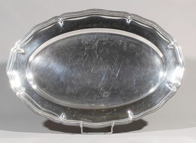an oval silver plate on a stand on a white surface
