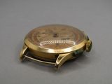 une montre en or avec un bracelet vert sur un fond gris