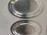 two oval silver trays sitting on a table