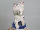 a ceramic vase with a bear on top of it