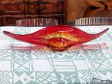 a red glass bowl sitting on a table with glasses on it