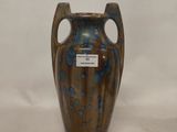 a blue and brown vase sitting on a white surface