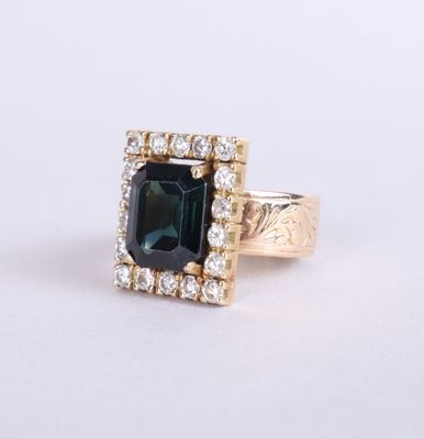 a close up of a ring with an emerald stone surrounded by diamonds