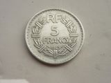 une pièce de 5 francs posée sur une surface blanche