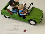 figurines of people riding in a green car with a certificate