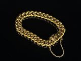 a gold chain bracelet with a clasp on a black background