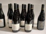 six bouteilles de vin sont alignées sur une surface blanche