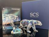 une figurine d'ours en cristal posée sur une table, à côté d'une boîte