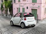 a small white car driving down a cobblestone street
