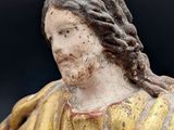 statue of a man with long hair holding a book