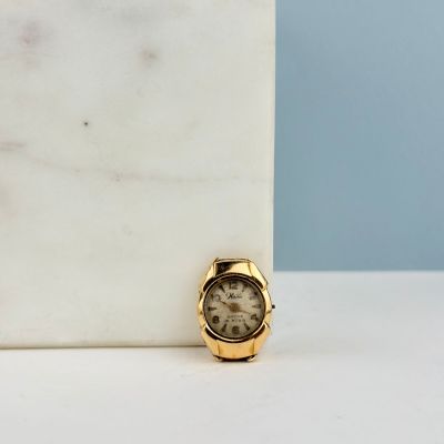 une petite montre en or posée sur un bloc de marbre