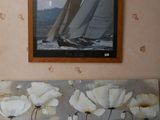 un tableau accroché au mur d'un salon, représentant un voilier