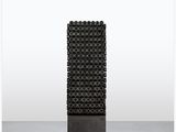 une sculpture noire posée sur un socle métallique, sur fond blanc