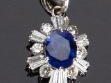 un gros plan d'un pendentif en saphir et diamants posé sur une surface noire