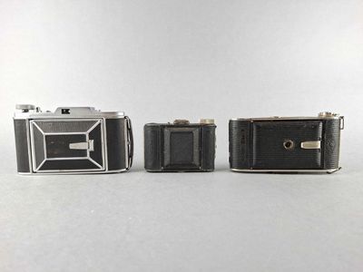 three old cameras sitting next to each other on a white surface
