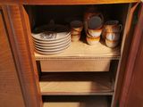 a cabinet with plates and cups on it in the kitchen
