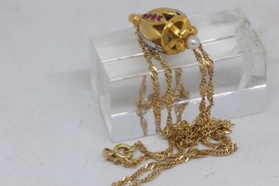a gold necklace with a skull on it sitting on a clear box