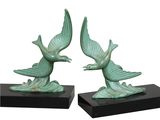 pair of green bird sculptures on black bases on white background