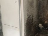 a white refrigerator in the middle of a dirty room