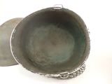 a metal bowl with a lid on a white surface