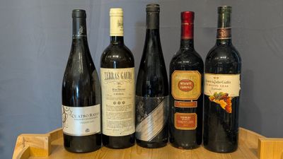 several bottles of wine are lined up on a wooden tray