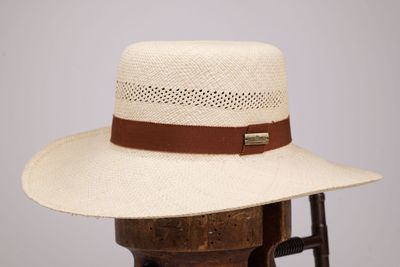 Ce chapeau est en paille et comporte un ruban en cuir