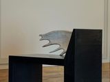 a sculpture of a dog sitting on a bench in the middle of a room