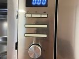 a stainless steel microwave with a digital clock on it