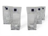 four clear glass vases are lined up on a white surface