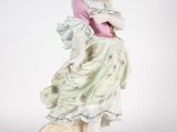 an antique porcelain figurine of a woman with a bird on her shoulder
