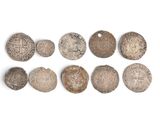Plusieurs pièces anciennes sont disposées en rangée sur une surface blanche