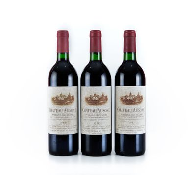 trois bouteilles de vin rouge posées l'une à côté de l'autre sur une surface blanche