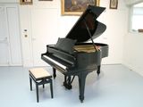 un piano noir posé dans une pièce avec un tabouret