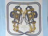 une écharpe bleue et dorée sur laquelle est représentée une paire de ciseaux