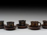 quatre tasses et soucoupes portant des chiffres, posées sur une table