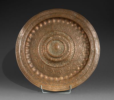 a large bronze plate with a circular design on a stand