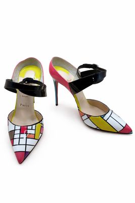 La femme porte une paire de chaussures colorées sur un fond blanc.