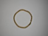 gros plan d'un bracelet en or sur une surface blanche