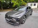 La voiture grise est garée sur le parking à côté d'une maison.