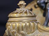 a gold vase with a figurine on it on a black background