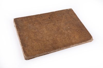 an old book sitting on top of a white table with a white background